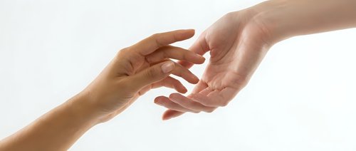 Two hands reaching toward each other in gentle connection against clean white background symbolizing help, support, trust and human compassion.
