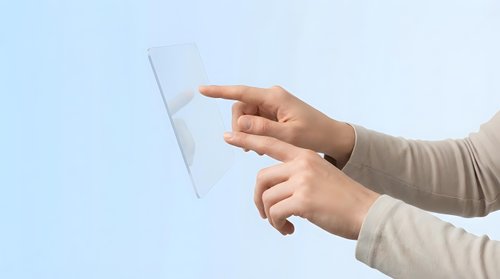 Hands holding transparent tablet computer with touchscreen interface against light blue background for modern technology concepts.