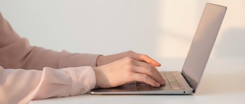 Professional woman hands typing on laptop computer at modern workspace during golden hour lighting for business productivity and remote work.