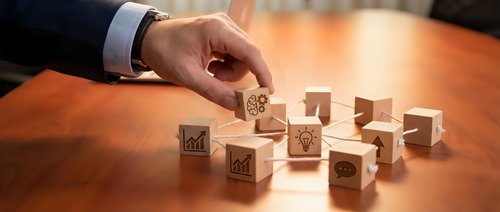 Businessman hand arranging wooden cubes with business icons on office desk representing strategic planning and organizational management concepts.
