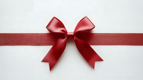 Red satin ribbon bow on white background for gift wrapping, holiday decorations, and festive design projects.