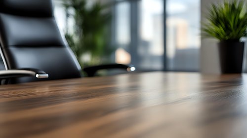 Empty modern conference room with wooden table and black leather chair, selective focus on polished surface, blurred office background with window and plant.