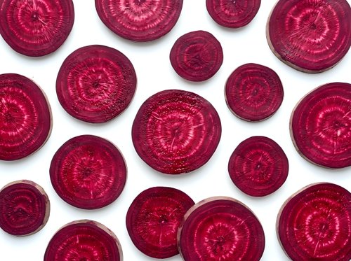 Fresh beetroot slices arranged on white background showing vibrant red color and natural ring patterns for healthy cooking and nutrition concepts.
