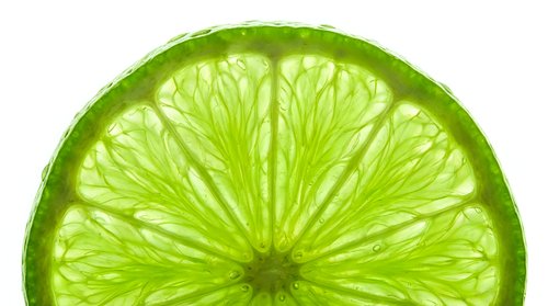 Lime slice half isolated on white background, fresh citrus fruit cross section with translucent segments for beverage, food and design projects.