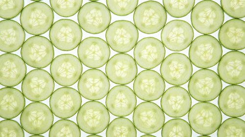 Fresh cucumber slices seamless pattern on light green background. Healthy vegetable texture for food design, spa wellness concepts, kitchen decor projects.