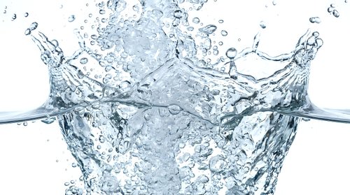 Clear water splash with ice cubes creating dynamic crown-shaped formation against white background. Fresh beverage concept for summer drinks and cooling refreshment.