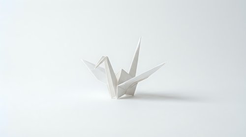 White origami paper crane folded from single sheet on clean white background. Minimalist Japanese art form symbol of peace and hope for creative projects.