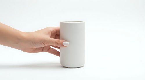 Female hand holding a minimalist matte white ceramic cup on white background, showcasing modern tableware design for lifestyle and product concepts.