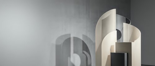 Modern minimalist architectural interior with curved geometric forms and soft lighting creating elegant shadows on textured wall surface.