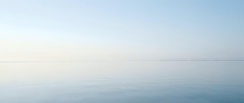 Serene misty seascape with calm waters and soft horizon, suitable for backgrounds, wellness, meditation, and tranquil design projects.