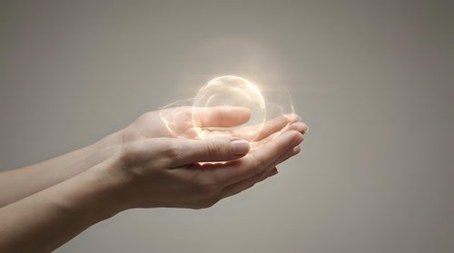 Hands holding glowing orb of light against neutral background, symbolizing innovation, energy, and future technology concepts for business and design projects.