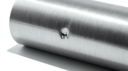 Brushed steel cylinder with small ant crawling on metallic surface showcasing scale and industrial texture for design projects.