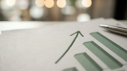 Business growth chart with upward arrow on desk with blurred office lights background for financial reports and presentations.