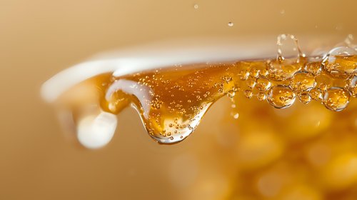Golden honey drip with bubbles captured in macro photography against warm amber background, showcasing viscosity and natural sweetness in food photography.