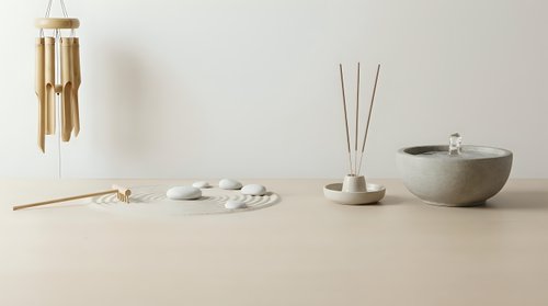 Minimalist zen spa arrangement with bamboo chimes, incense sticks, ceramic bowls and natural elements on wooden surface for wellness and meditation.