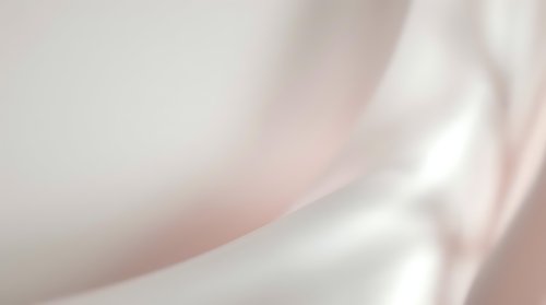 Soft pink and white silk fabric with elegant flowing curves and gentle waves creating luxurious textile background for fashion and beauty projects.