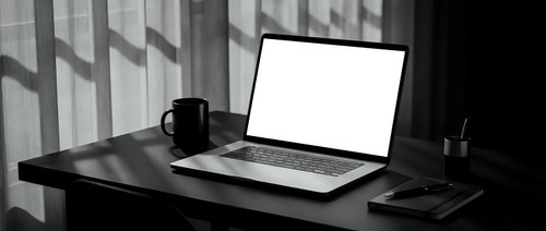 Modern minimalist workspace with open laptop displaying blank white screen on dark wooden desk with coffee mug and office supplies in monochrome setting.
