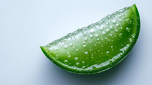 Fresh lime wedge with water droplets on bright surface, macro shot showing juicy citrus texture and natural moisture against white background.