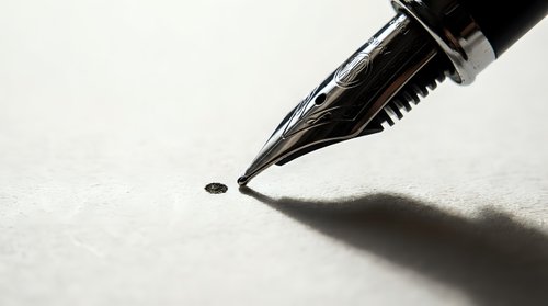 Close-up of elegant fountain pen nib touching paper surface with ink dot, creating dramatic shadow. Professional writing instrument for business documents.