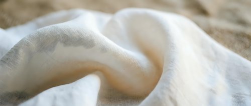 Soft white cotton fabric with gentle folds and natural texture creating elegant drapery for home decor and textile design projects.