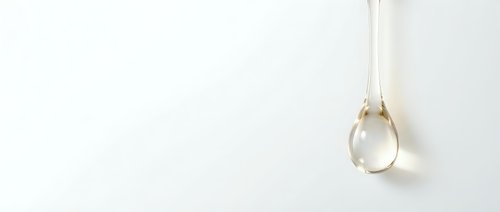 Transparent water droplet suspended from string against white background, isolated design element for graphic projects and digital compositions.