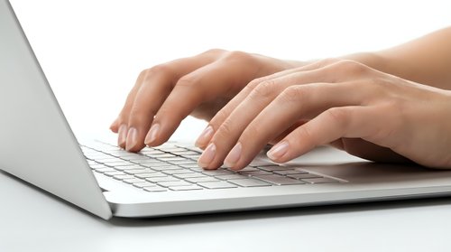 Hands typing on laptop keyboard in modern office workspace for business communication and productivity tasks.