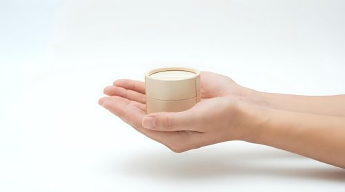 Female hands holding luxury skincare cream jar with gold cap against white background for beauty and cosmetics advertising campaigns.