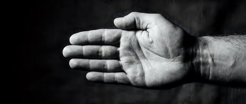 Male hand with open palm gesture against dark textured background, conveying offering, acceptance, or help concept for business and communication designs.