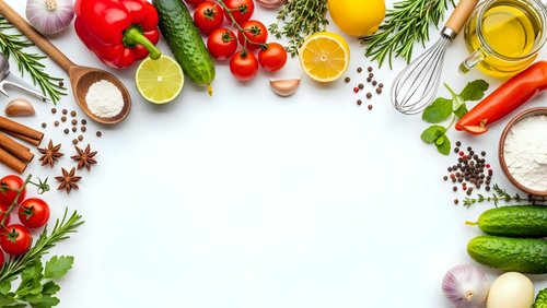 Fresh organic vegetables, herbs and cooking ingredients arranged in circular frame on white background with copy space for culinary design projects.