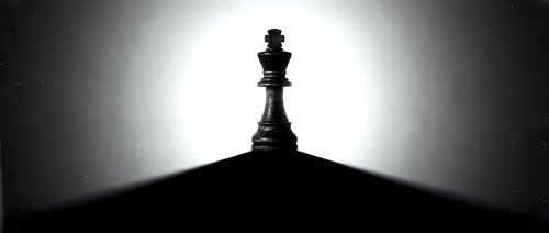 Queen chess piece silhouetted against bright backlit glow, symbolizing leadership, strategy, and power for business and game concepts.