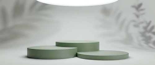Minimalist sage green cylindrical podiums on white surface with soft lighting and botanical shadows for product display and branding presentations.
