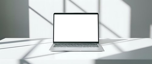 Modern laptop computer with blank white screen on minimalist desk with dramatic window shadow patterns for mockup presentations and digital workspace concepts.