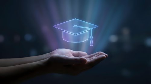 Glowing graduation cap hologram floating above open hands against dark background with bokeh lights for education and achievement concepts.