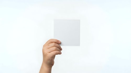 A hand holding a blank white card or paper against a neutral background, suitable for mockups, advertising, and promotional designs.