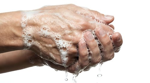 Hands washing with soap and water, proper hygiene routine for health and cleanliness. Male hands with wedding ring under running water with soap bubbles.