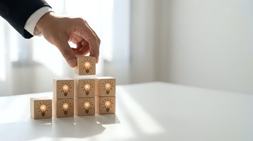 Businessman hand placing wooden cube with lightbulb icon on stack representing innovation, creativity and business solution development in office.