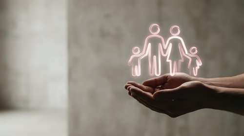 Glowing family protection concept with neon pink figures floating above cupped hands against concrete wall background for insurance and care themes.