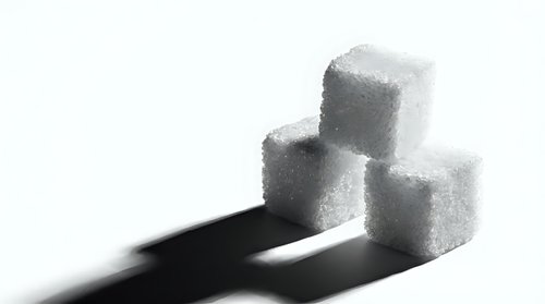 Stacked white sugar cubes casting dark shadows on isolated white background, suitable for nutrition, health, diet and food industry design projects.