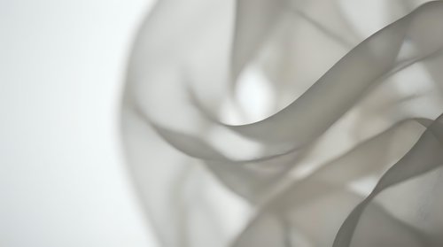 Soft flowing fabric waves creating abstract layers of translucent material with gentle shadows and highlights, suitable for backgrounds, textile design, and contemporary visual projects.
