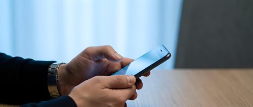 Professional businessman using smartphone at office desk for mobile communication and digital business tasks.