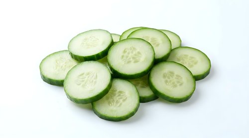 Fresh cucumber slices arranged on white background, perfect for healthy eating concepts, cooking ingredients, and culinary designs.