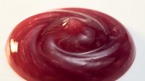 Rich burgundy red swirl texture with glossy finish creating smooth flowing patterns for culinary and design applications.