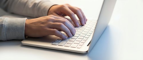Professional hands typing on modern laptop keyboard in bright office environment for business and technology applications.