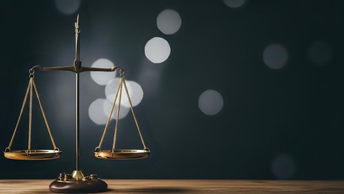 Golden brass scales of justice on wooden surface with soft bokeh lights background for legal and law firm presentations.