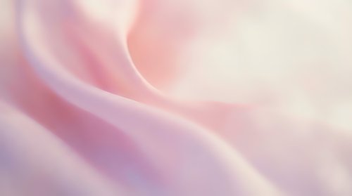 Soft pink silk fabric with smooth flowing folds and gentle waves, creating an elegant pastel texture background for luxury design projects.