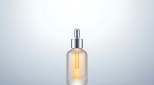 Luxury skincare serum bottle with golden oil and dropper cap on gradient background for cosmetic product photography and beauty branding materials.