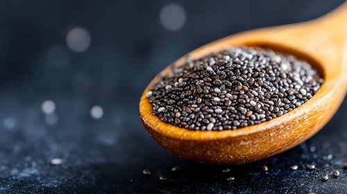 Organic chia seeds in wooden spoon on dark background with bokeh effect. Healthy superfood rich in omega-3 and fiber. Close up macro photography.
