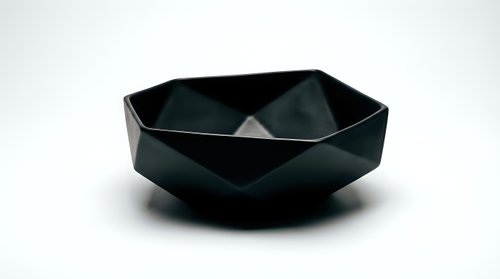 Matte black geometric faceted bowl with angular design on white background, isolated for modern interior, product, and design projects.