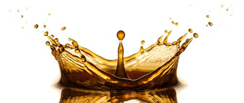 Golden liquid splash forming crown shape with droplets against white background for beverage advertising and product design.