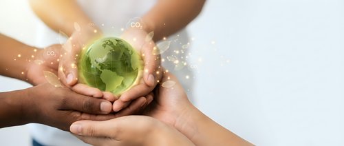 Diverse hands protecting green earth globe with sparkling light effects symbolizing global environmental protection and sustainability teamwork.